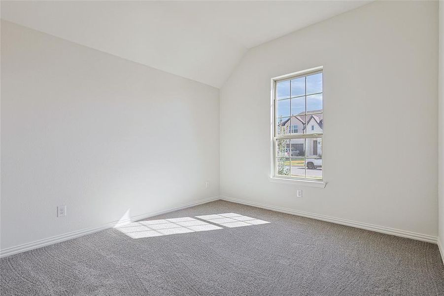 Spare room featuring lofted ceiling and light colored carpet