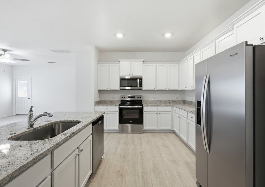 Kitchen featuring a granite island with undermount sink, white cabinetry, and stainless appliances. Kitchen featuring a granite island with undermount sink, white cabinetry, and stainless appliances.