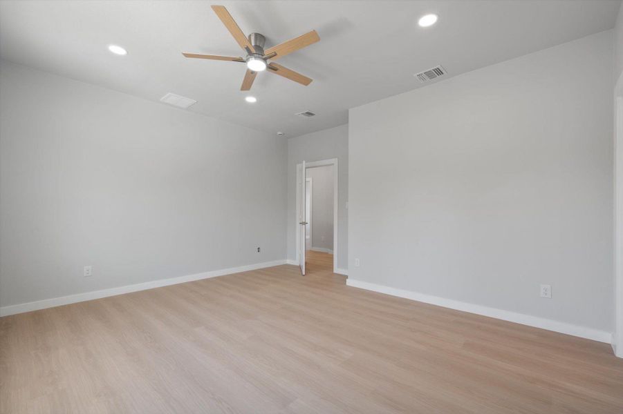 A naturally illuminated room features light wood flooring and a modern ceiling fan with recessed lighting.