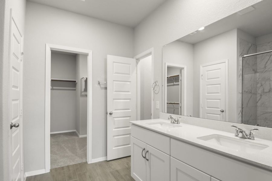 Image of a primary bathroom with white cabinets and a jack and jill vanity with a connecting walk-in closet Image of a primary bathroom with white cabinets and a jack and jill vanity with a connecting walk-in closet