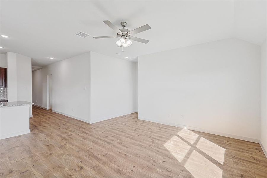 Unfurnished living room featuring ceiling fan, lofted ceiling, and light wood-type flooring