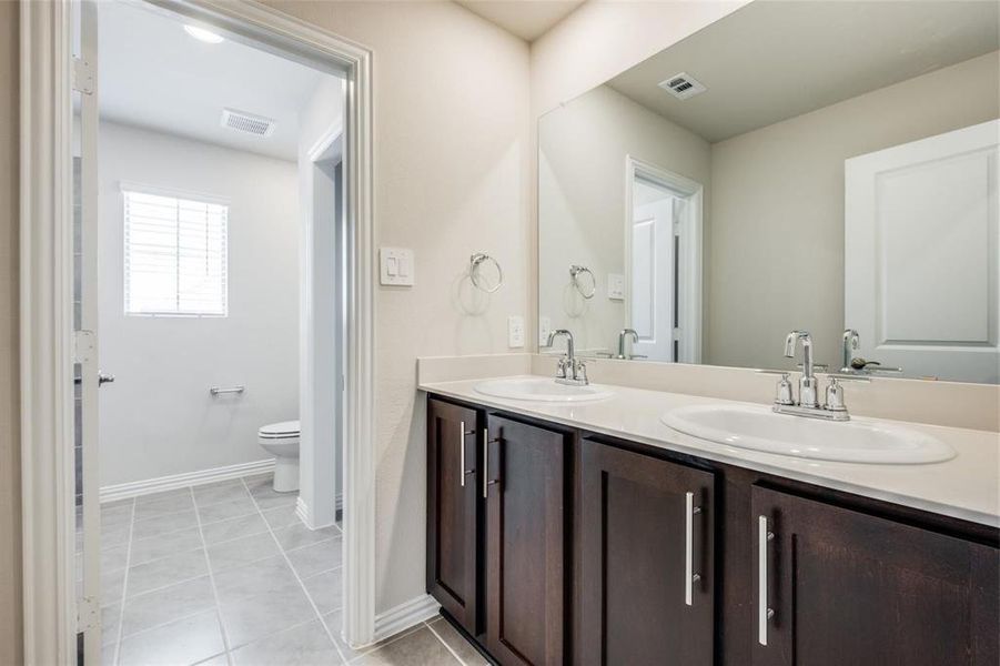 Bathroom featuring dual vanity, tile patterned flooring, and toilet