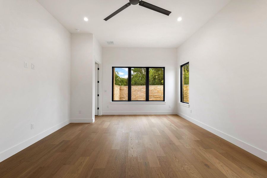Spacious room featuring wood-finish flooring, recessed lighting, and a contemporary ceiling fan