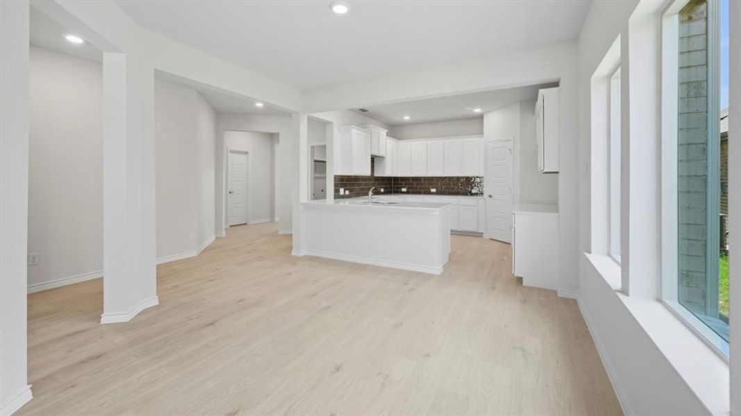 Kitchen featuring white cabinets, light wood-type flooring, decorative backsplash, recessed lighting, and a peninsula Kitchen featuring white cabinets, light wood-type flooring, decorative backsplash, recessed lighting, and a peninsula