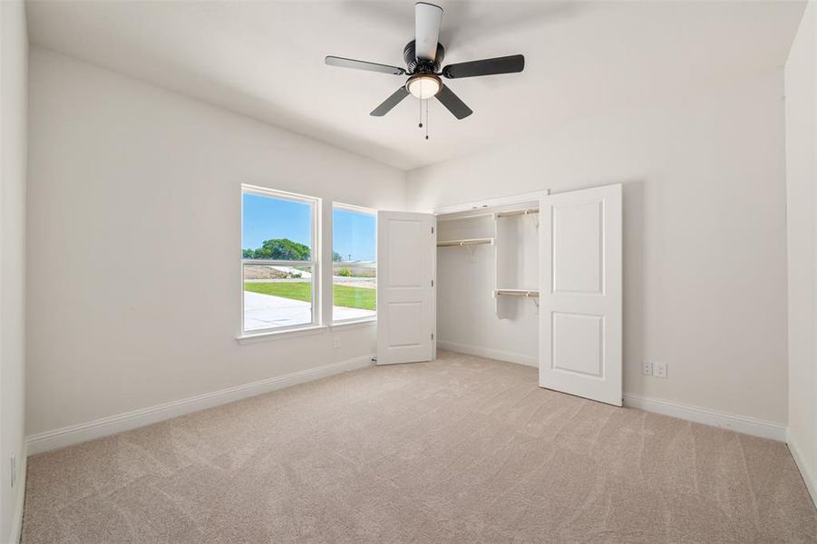 Unfurnished bedroom featuring light colored carpet, a closet, and ceiling fan