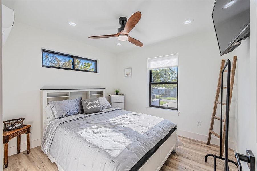 Bedroom with light wood finished floors, ceiling fan, and recessed lighting