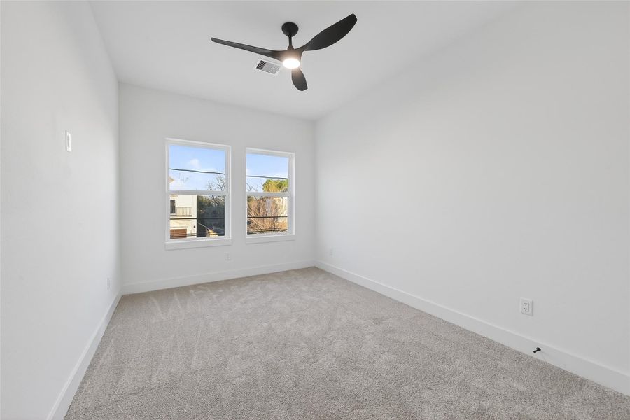 This room features a spacious layout with clean white walls. It has large windows for natural light and a modern ceiling fan with recessed lighting, creating a bright and airy atmosphere. This room features a spacious layout with clean white walls. It has large windows for natural light and a modern ceiling fan with recessed lighting, creating a bright and airy atmosphere.