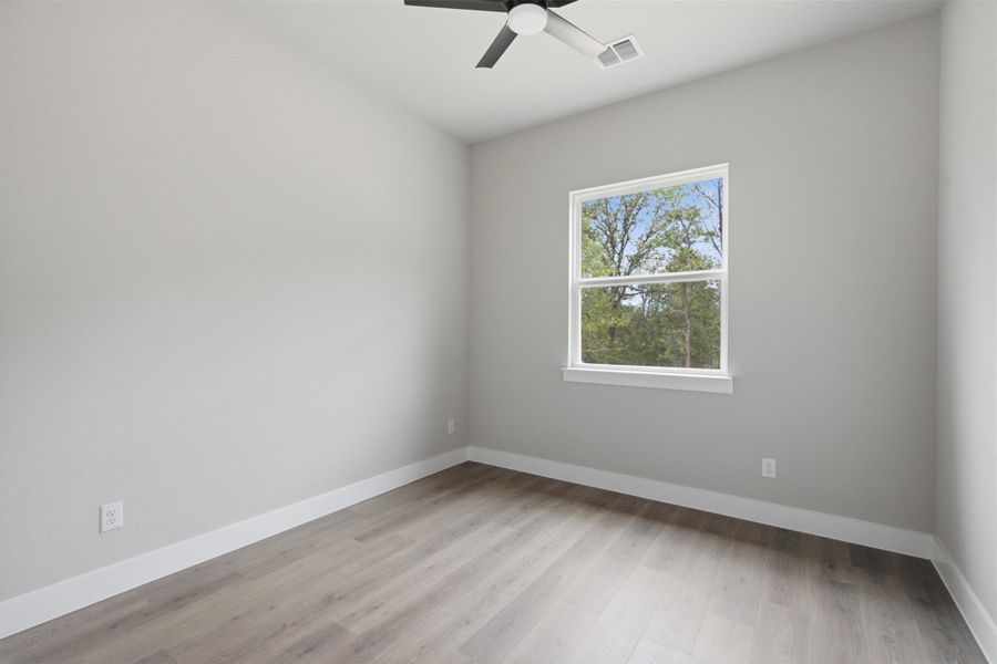 A well-lit bedroom features durable laminate flooring and a ceiling fan for comfort. A well-lit bedroom features durable laminate flooring and a ceiling fan for comfort.