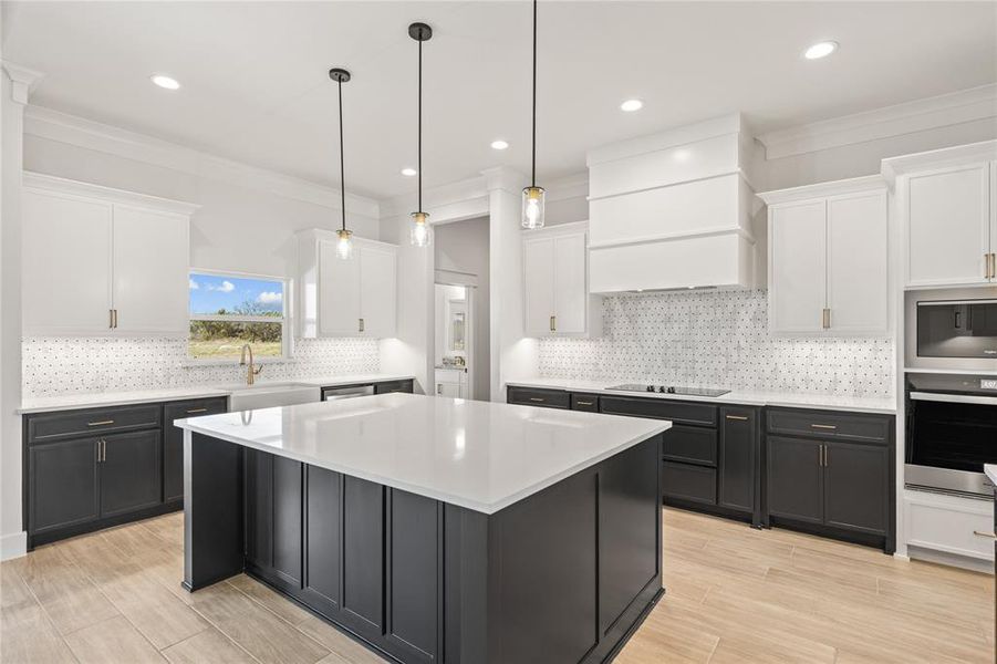 Kitchen featuring dual tone cabinetry, crown molding, a kitchen island, stainless steel appliances, and decorative backsplash