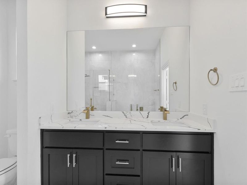 Bathroom with toilet, double vanity, a stall shower, and recessed lighting
