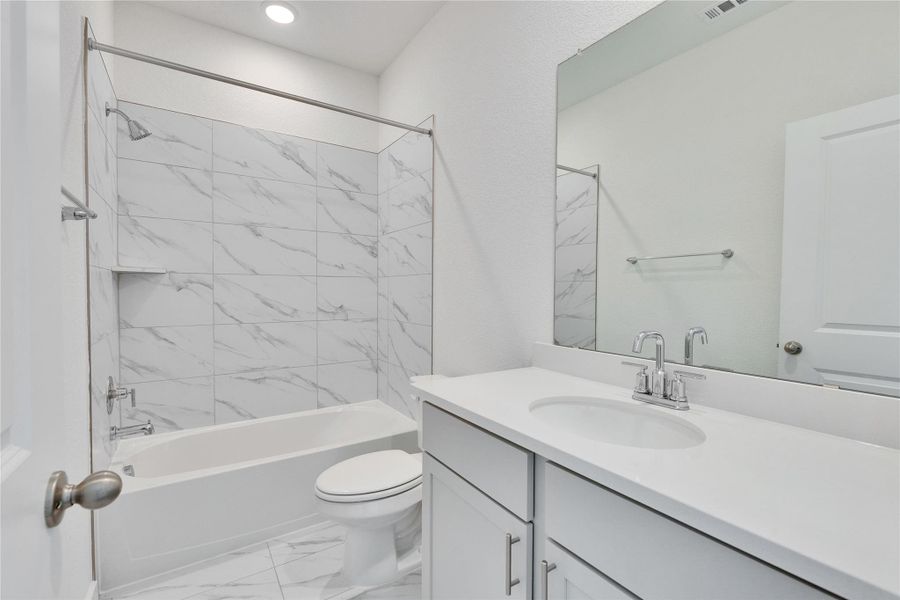 Bathroom with bathtub / shower combination, vanity, and light marble finish floors