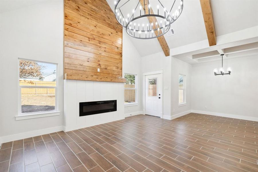 Unfurnished living room featuring a notable chandelier, beam ceiling, high vaulted ceiling, and dark hardwood / wood-style floors