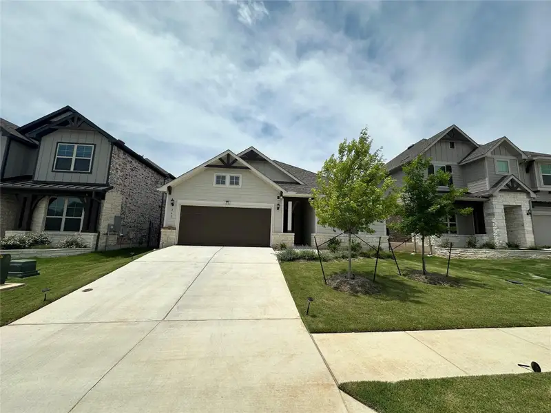 Craftsman-style home featuring a light-toned exterior, dark garage door, and decorative gable accents Craftsman-style home featuring a light-toned exterior, dark garage door, and decorative gable accents