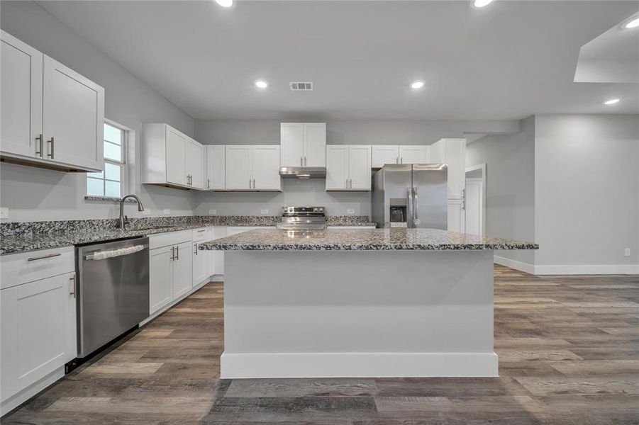 Kitchen featuring stainless steel appliances, sink, a kitchen island, and white cabinets