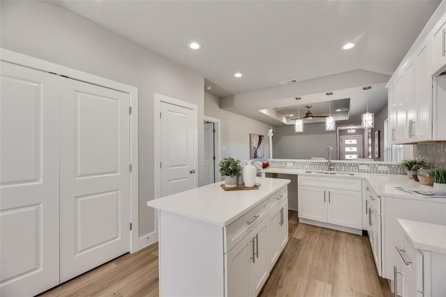 Kitchen with sink, light hardwood / wood-style flooring, decorative light fixtures, and kitchen peninsula