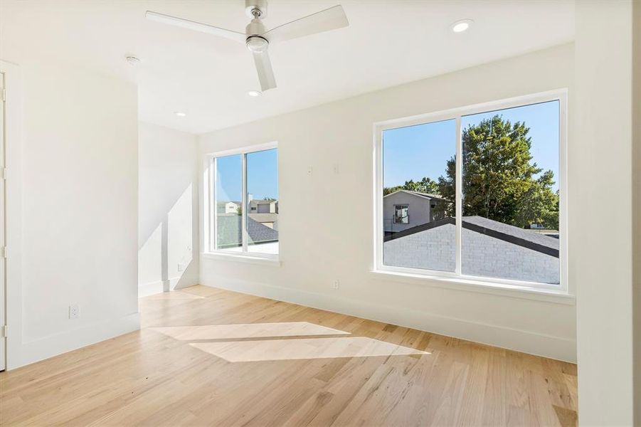 Empty room with ceiling fan, a wealth of natural light, and light hardwood / wood-style flooring