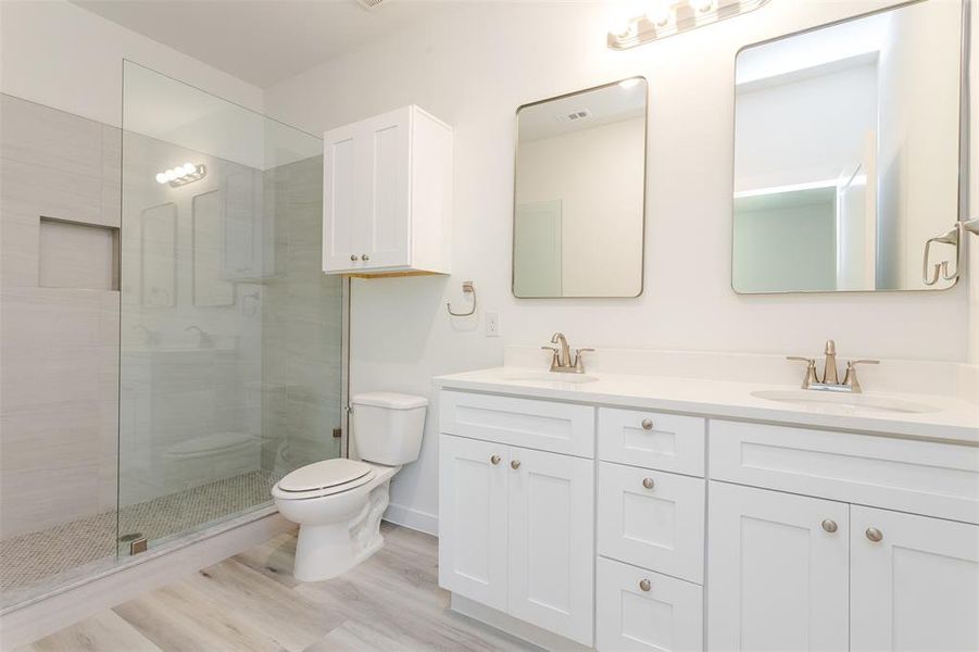 Bathroom with walk in shower, toilet, hardwood / wood-style floors, oversized vanity, and dual sinks