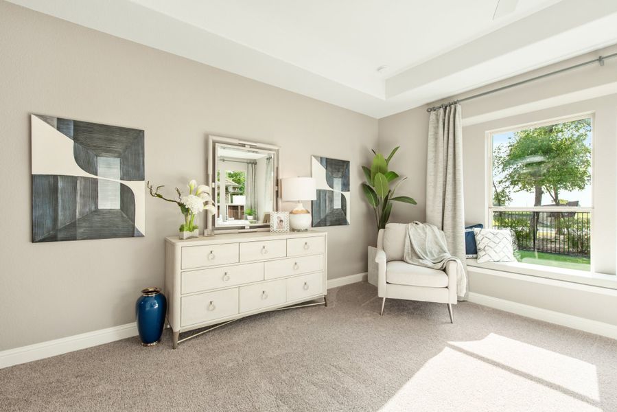 Bedroom sitting area with white dresser, accent chair, and large window with outdoor views