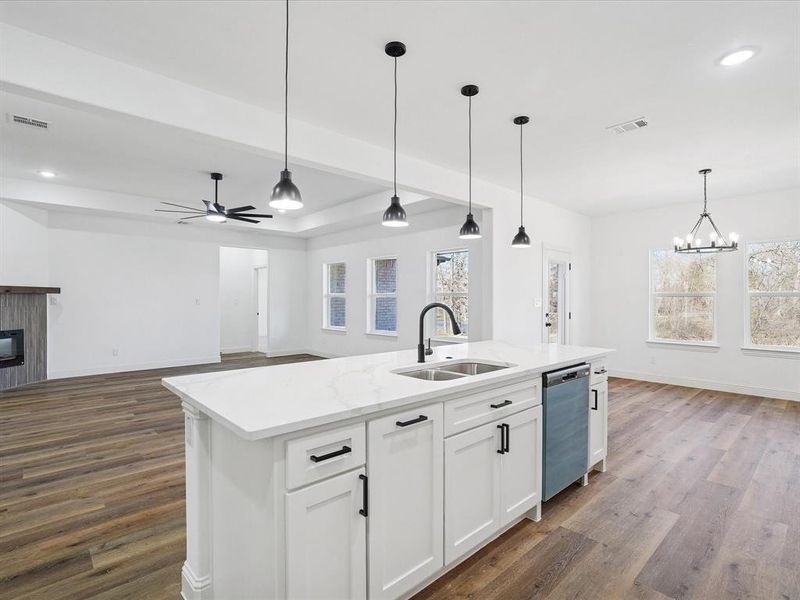 Kitchen with open floor plan, a glass covered fireplace, suspended lighting, white cabinets, and dark wood-style floors