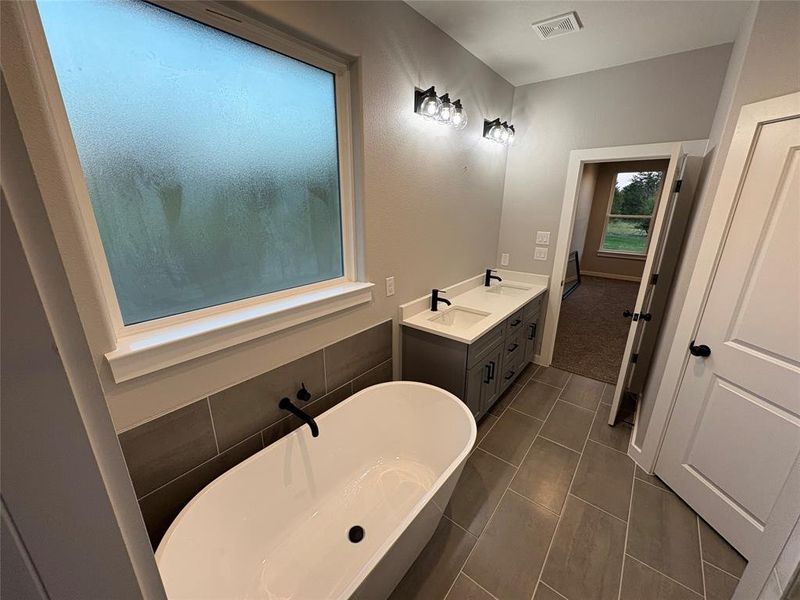 Bathroom featuring vanity, a bath, and tile patterned flooring