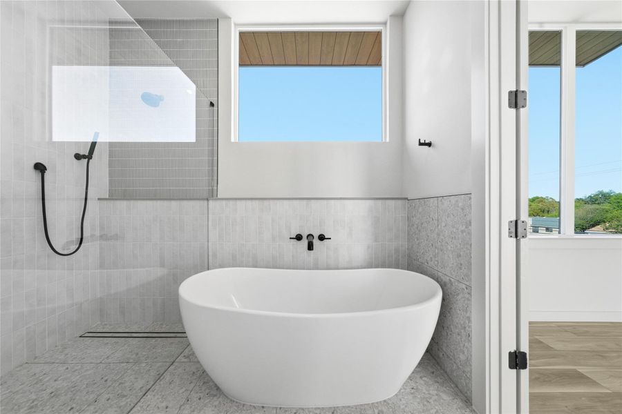 Full bath with a soaking tub, a walk in shower, wainscoting, and tile walls Full bath with a soaking tub, a walk in shower, wainscoting, and tile walls