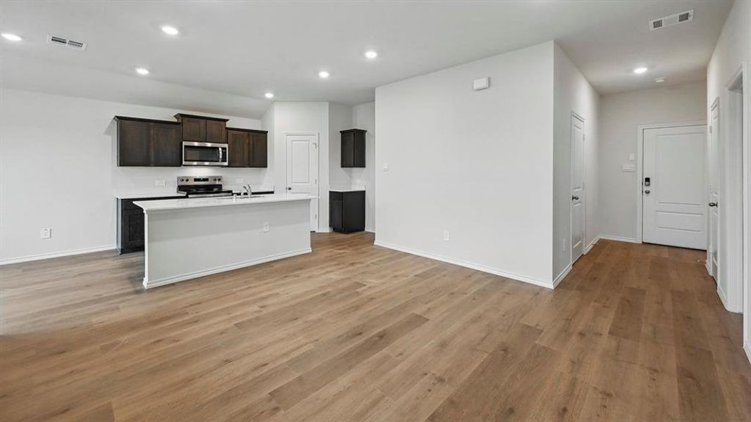 Kitchen with a center island with sink, recessed lighting, stainless steel appliances, light wood-style flooring, and open floor plan