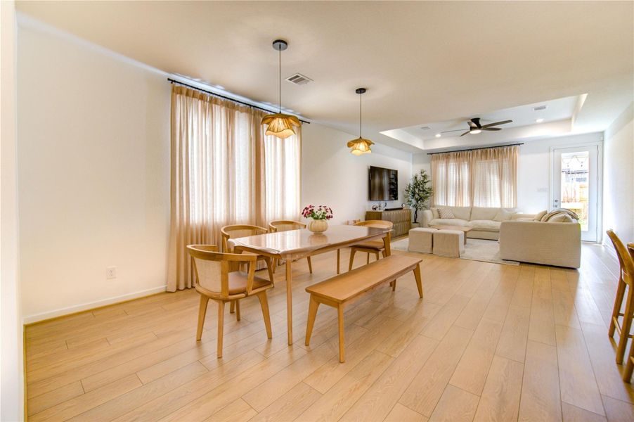 The formal dining room offers an ideal setting for both everyday meals and entertaining. High ceilings, a stylish light fixture, and abundant natural light create a welcoming atmosphere, while the bright tones of the vinyl flooring add depth and charm. The open layout seamlessly connects this space to the gourmet kitchen and main living area, enhancing flow and functionality.