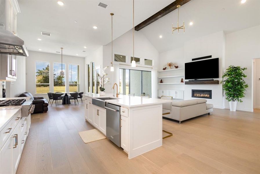 Kitchen with open floor plan, a chandelier, white cabinetry, a glass covered fireplace, and hanging light fixtures
