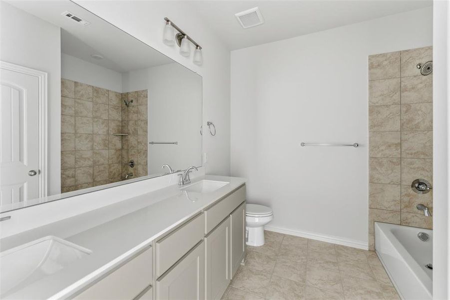 Full bath with double vanity,  shower combination, and light tile patterned floors