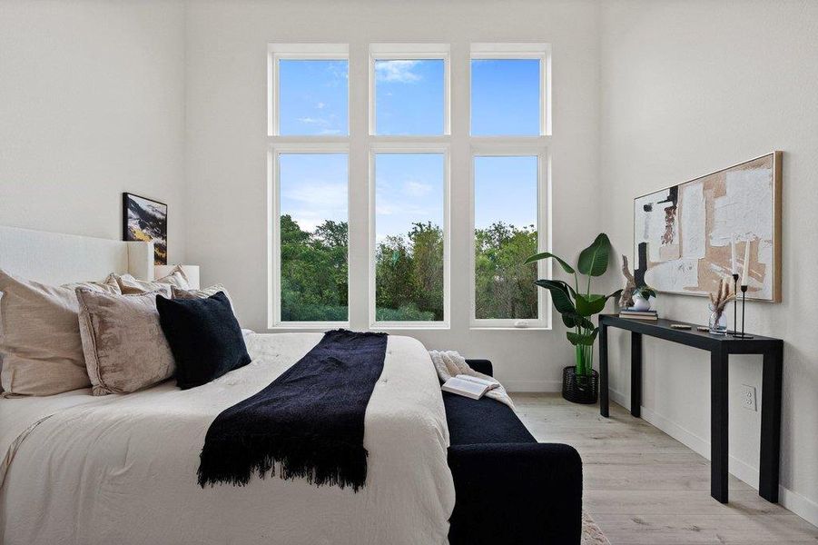 This room features large windows with expansive views of lush greenery, complemented by light-toned flooring