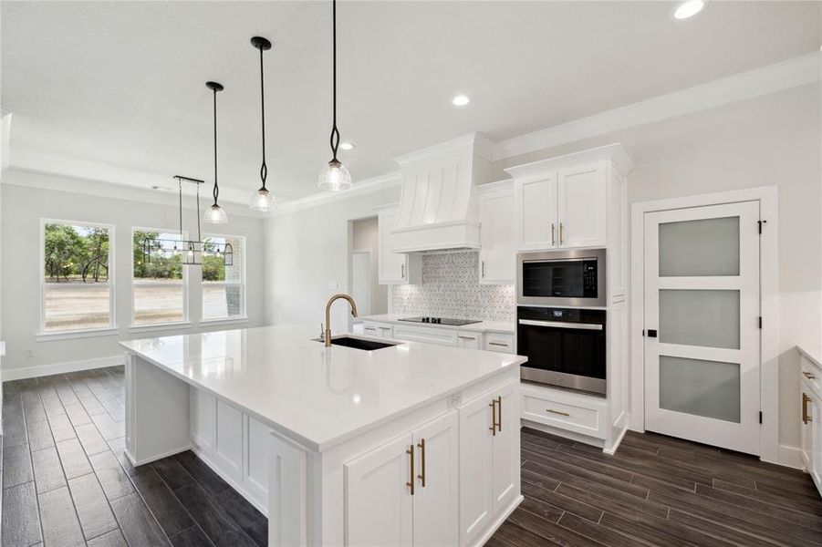 Kitchen featuring tasteful backsplash, stainless steel appliances, an island with sink, sink, and custom range hood