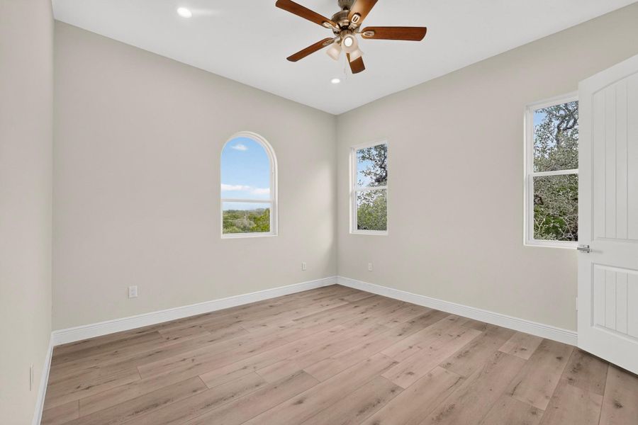 Arched and rectangular windows frame serene outdoor views across the wood floors.