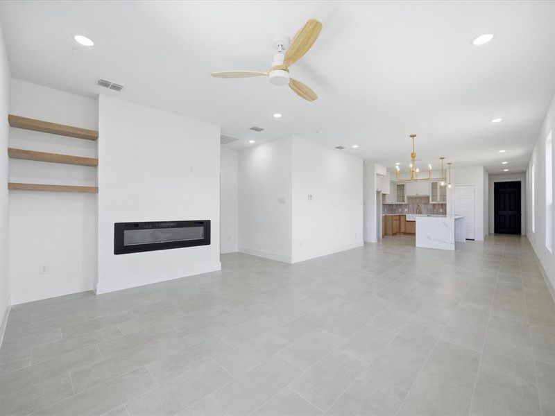 Unfurnished living room with ceiling fan, recessed lighting, a glass covered fireplace, and light tile patterned flooring