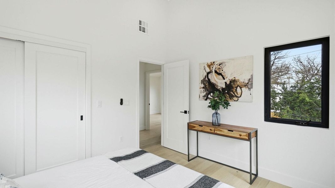 Bedroom featuring light wood-style flooring, a closet, and a high ceiling