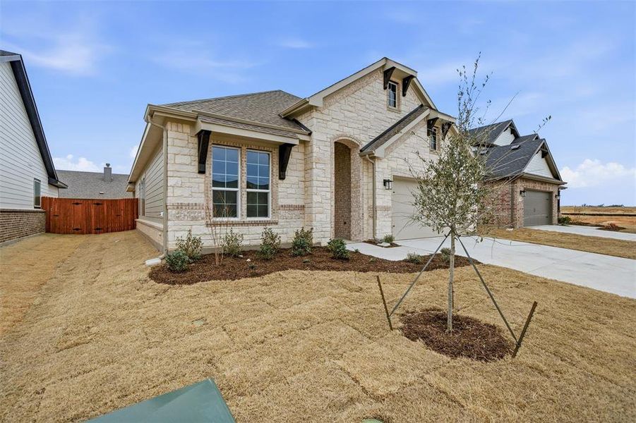 View of front of home featuring stone siding, driveway, a gate, and a shingled roof