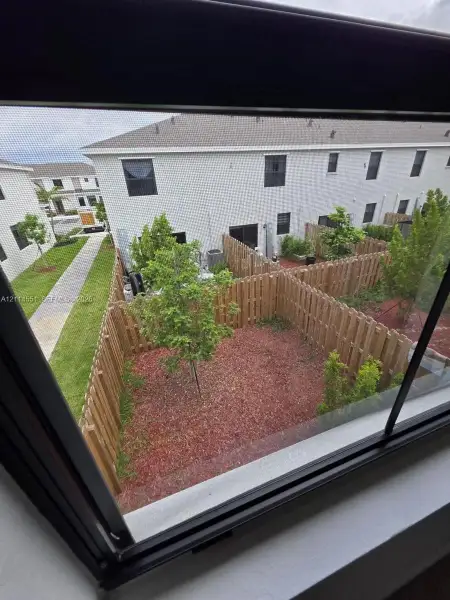 Exterior courtyard featuring wood privacy fencing, gravel ground cover, and ornamental trees