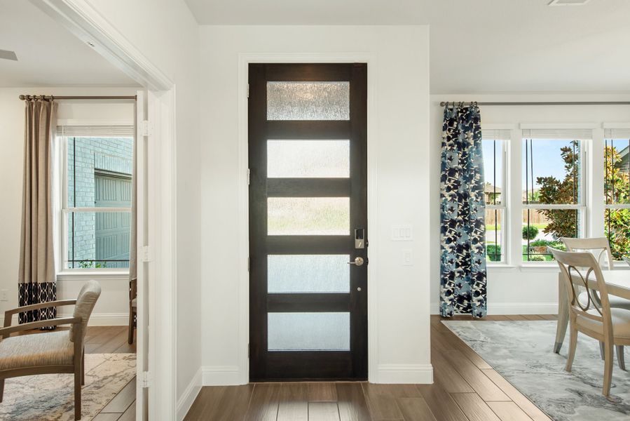Dark wood front door with five frosted glass panels in a bright entryway with hardwood floors