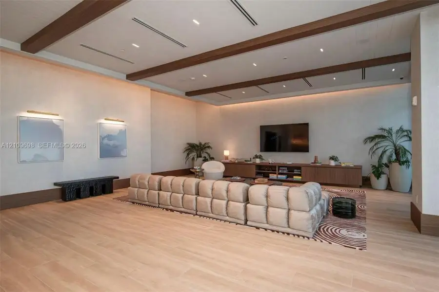 Recessed lighting, wood-finish ceiling beams, wood-finish flooring, built-in media console, and wall-mounted art lighting