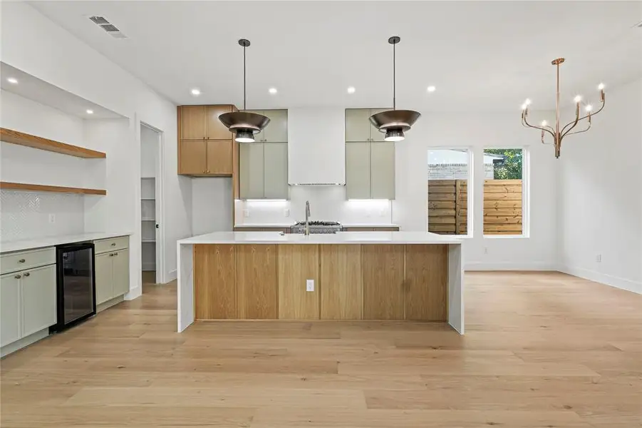 Kitchen with pendant lighting, light stone counters, open shelves, light wood-style flooring, and recessed lighting
