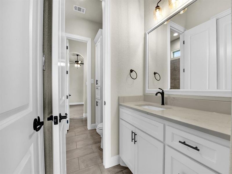 Bathroom with tile patterned flooring, ceiling fan, toilet, and vanity