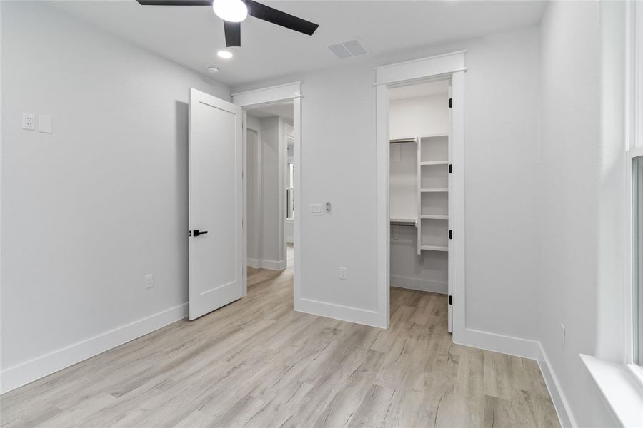 Unfurnished bedroom featuring recessed lighting, light wood-style flooring, a ceiling fan, and a spacious closet