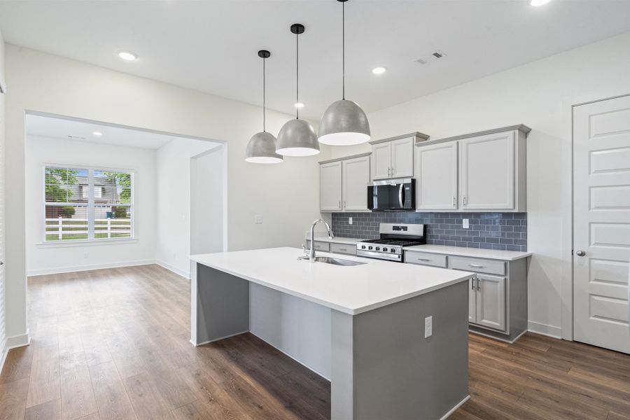 Kitchen featuring gray cabinets, stainless steel appliances, a kitchen island with sink, dark wood-type flooring, and pendant lighting