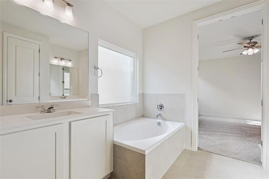 Bathroom featuring vanity, tiled bath, tile patterned flooring, and ceiling fan