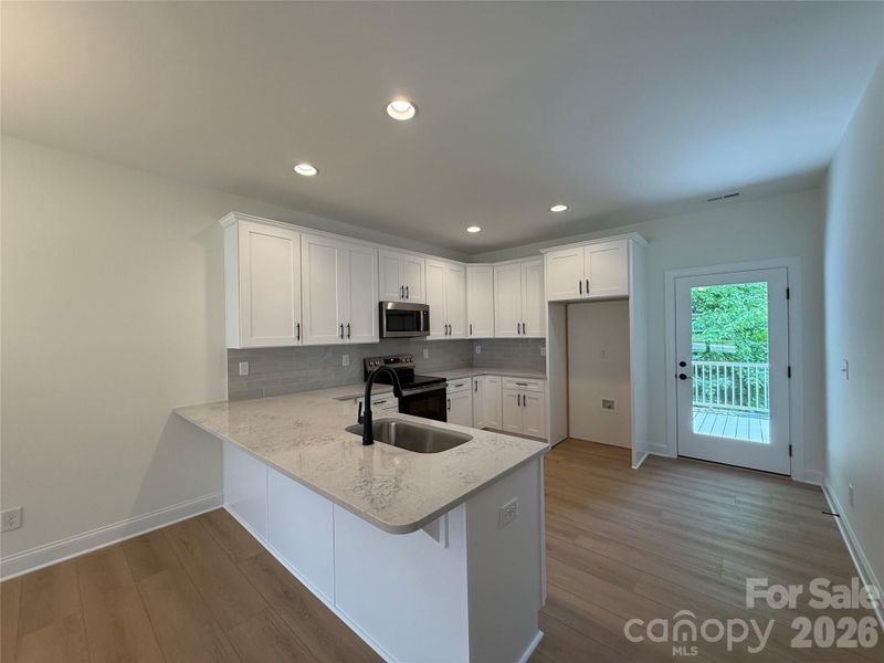 The kitchen offers a spacious breakfast bar, access to the back deck through a glass door,...