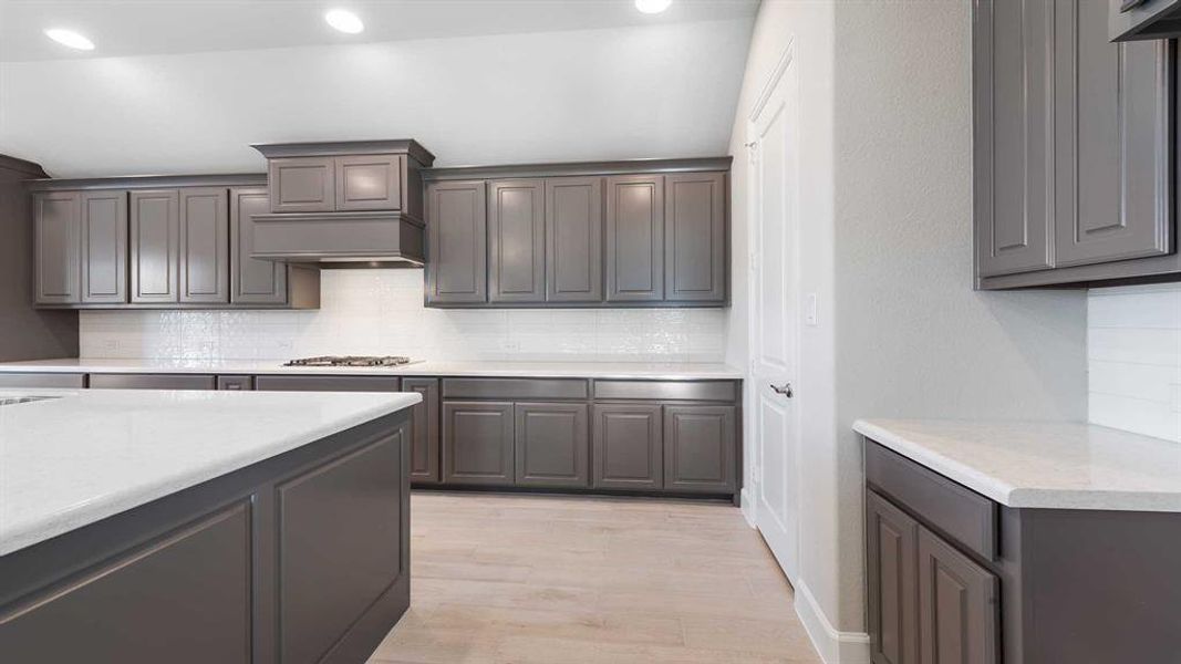 Kitchen with backsplash, light hardwood / wood-style flooring, and stainless steel gas cooktop