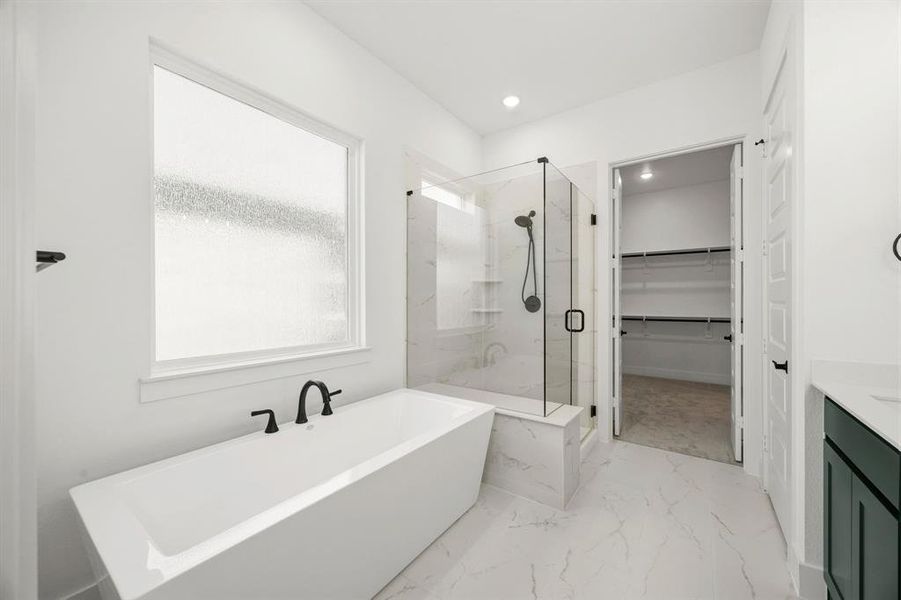Full bath featuring a marble finish shower, vanity, a spacious closet, a soaking tub, and recessed lighting