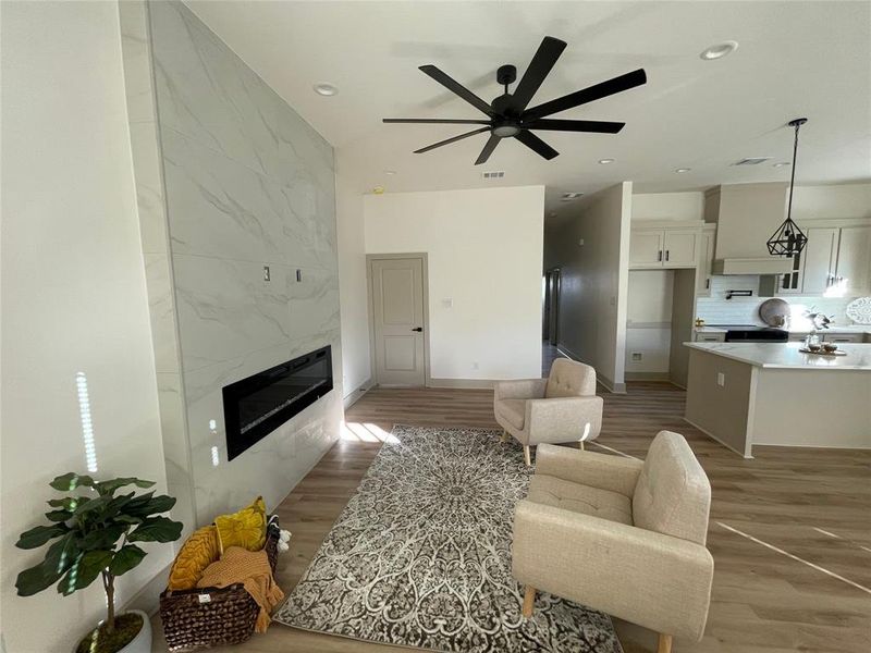 Living room with ceiling fan, light wood-type flooring, and a fireplace