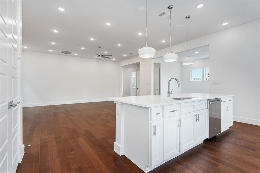 Kitchen featuring white cabinetry, dishwasher, dark hardwood / wood-style flooring, sink, and a center island with sink