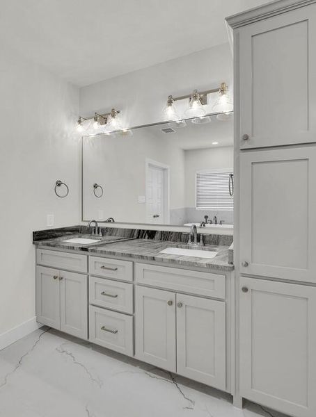 Full bathroom featuring double vanity and light marble finish floors