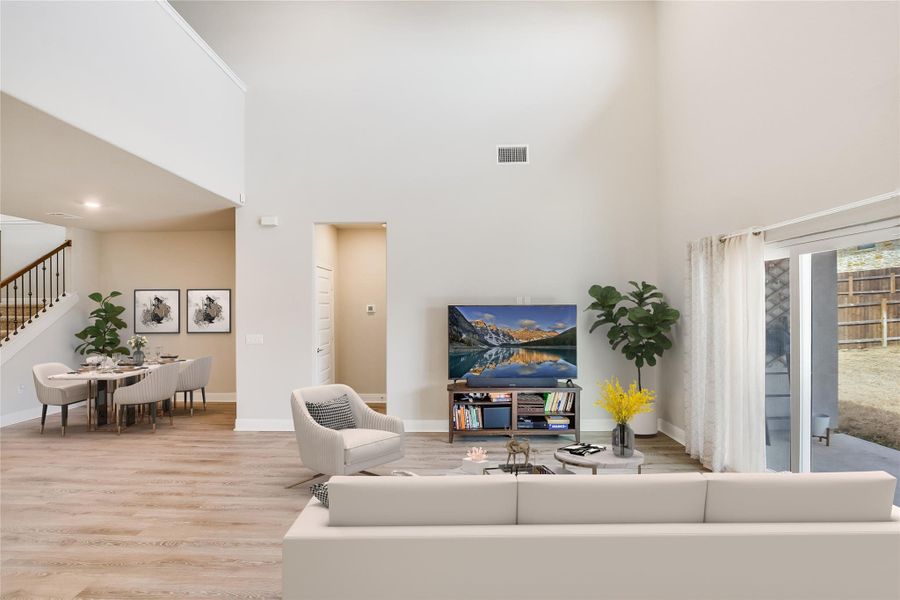 Living room featuring stairway, visible vents, a towering ceiling, and wood finished floors